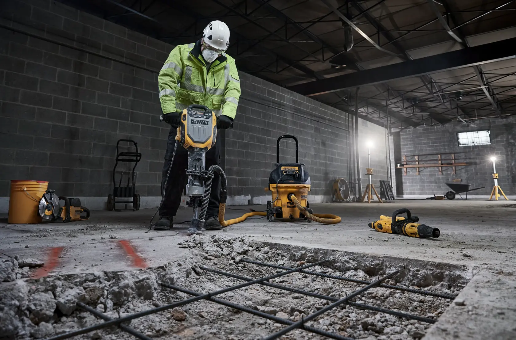 Arbeiter nutzt DEWALT D25966, D25966-B2 Abbruchhammer für Beton im Lager. Bauwerkzeuge sichtbar.