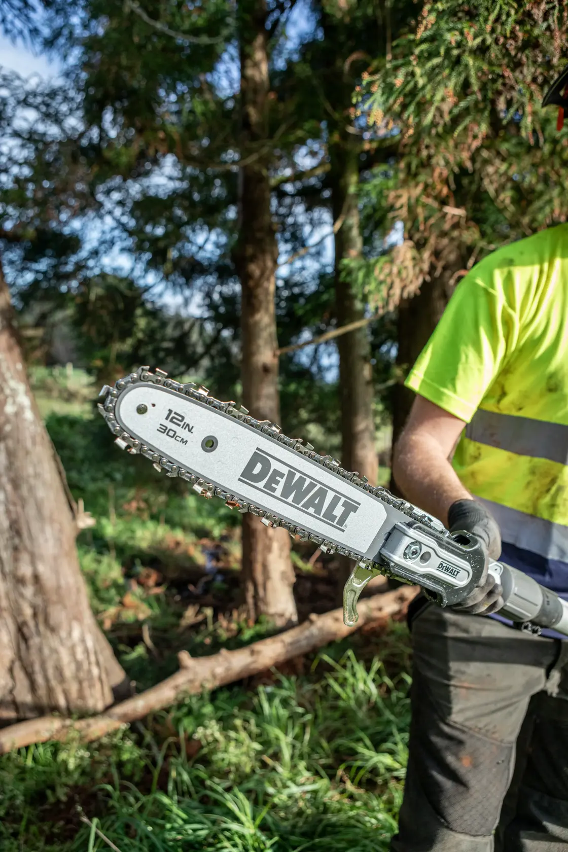 DEWALT Hochentaster mit 12-Zoll-Blatt, draußen gehalten von Person mit Handschuhen und Warnkleidung.