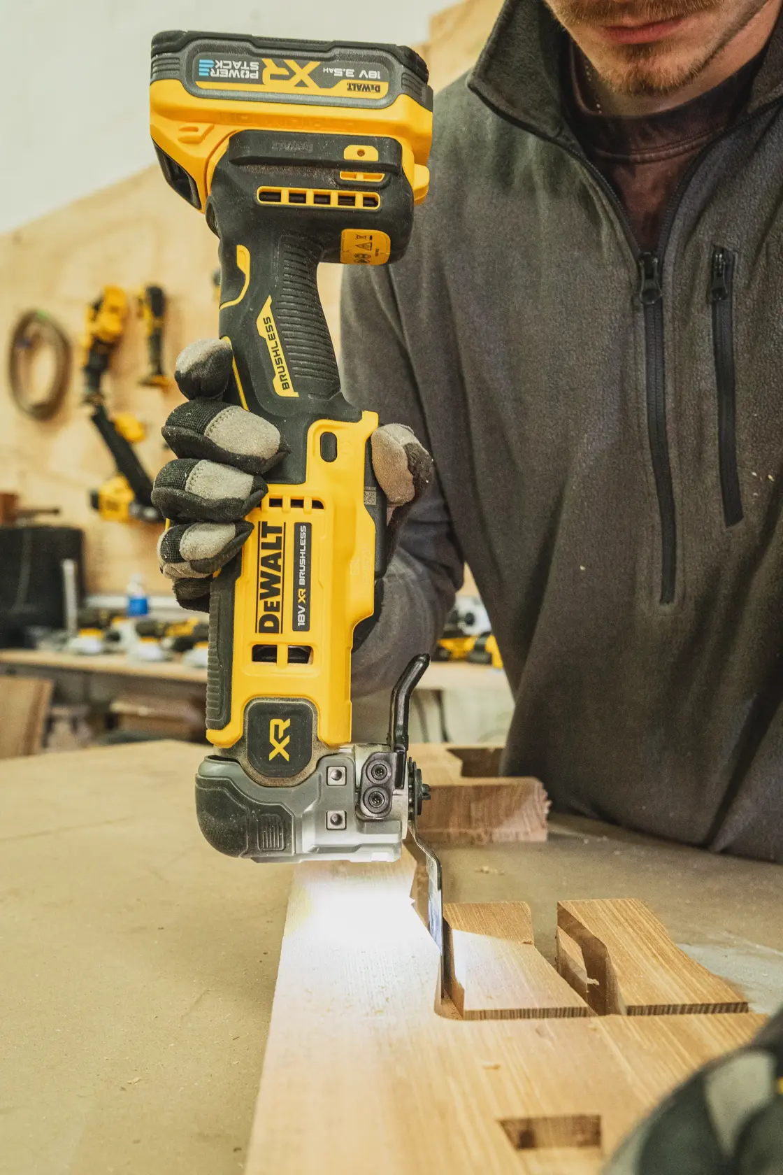 Person benutzt DEWALT Akku-Stichsäge zum Schneiden von Holz auf einer Werkbank.