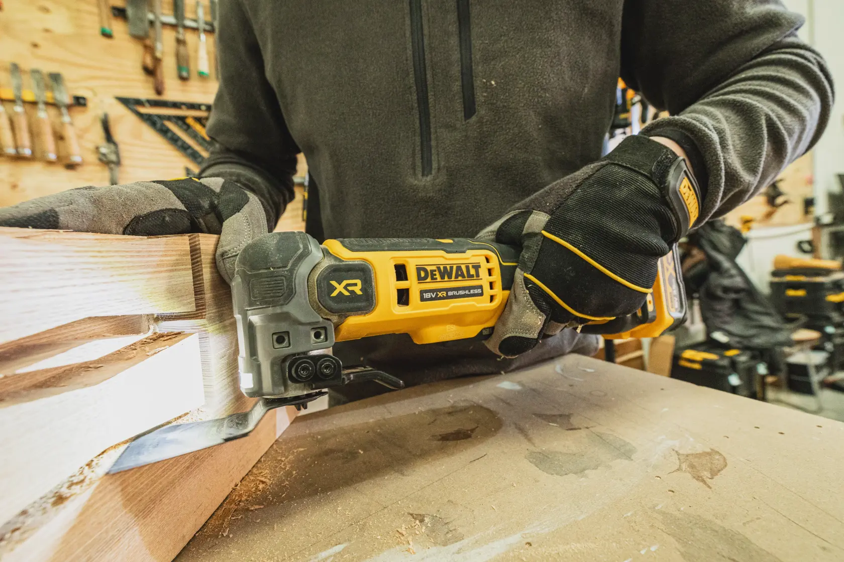 Person nutzt DEWALT XR bürstenloses Werkzeug zum Holzschneiden in einer Werkstatt, mit Handschuhen.