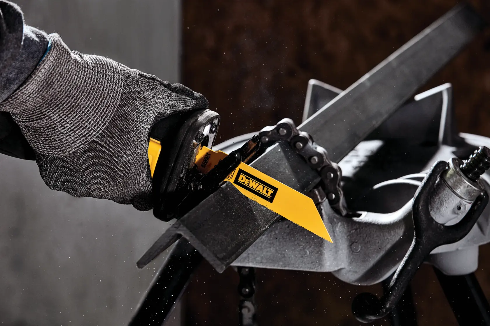 Eine Person mit Sicherheitshandschuhen verwendet ein DEWALT-Sägeblatt für eine Säbelsäge, um eine Metallstange zu schneiden. Das gelbe DEWALT-Sägeblatt zeigt deutlich das Markenlogo. Die Szene spielt in einer Werkstatt.