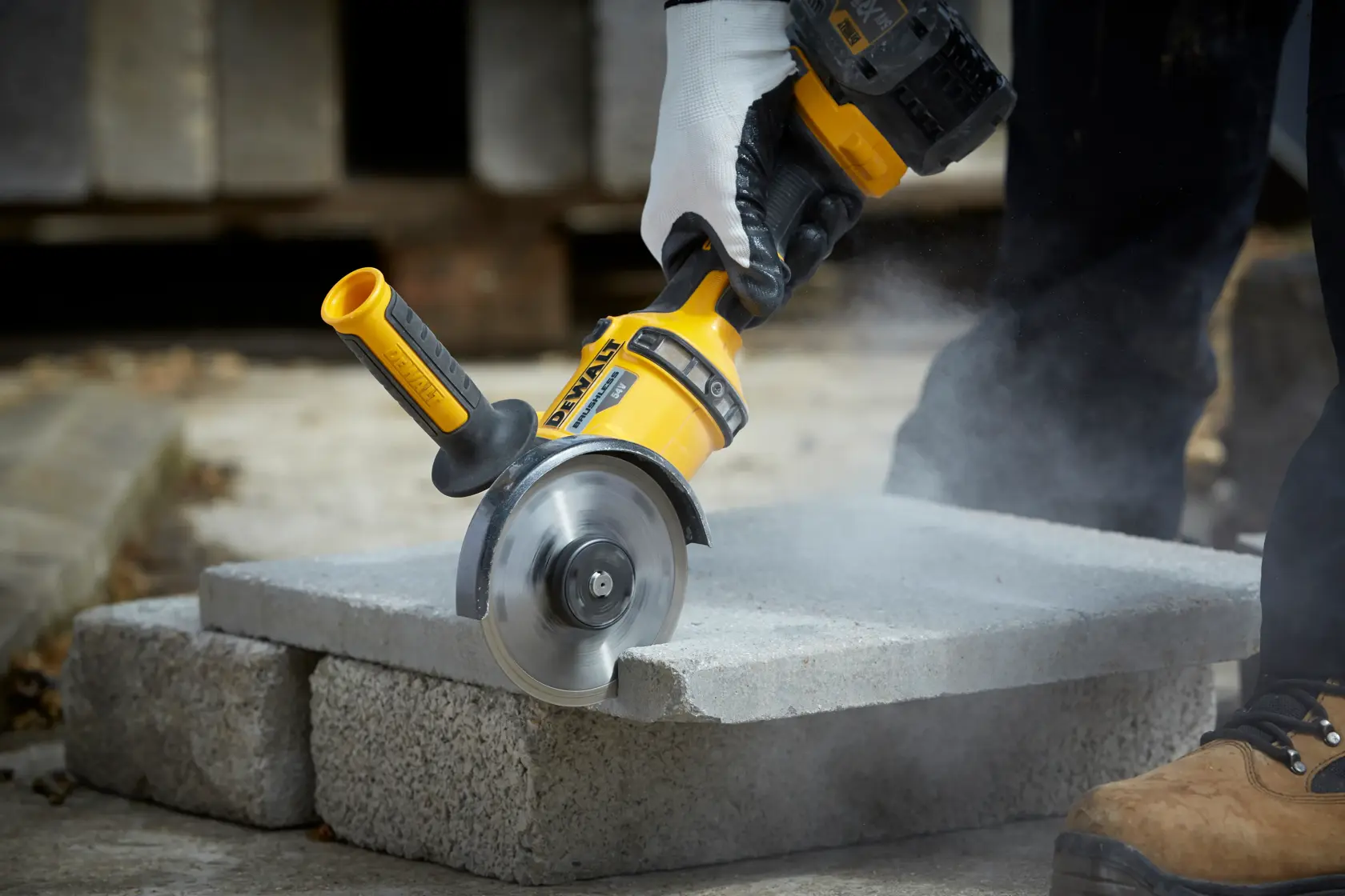 DEWALT DT3712 Werkzeug schneidet Betonblock außen, Staub und behandschuhte Hand sichtbar.