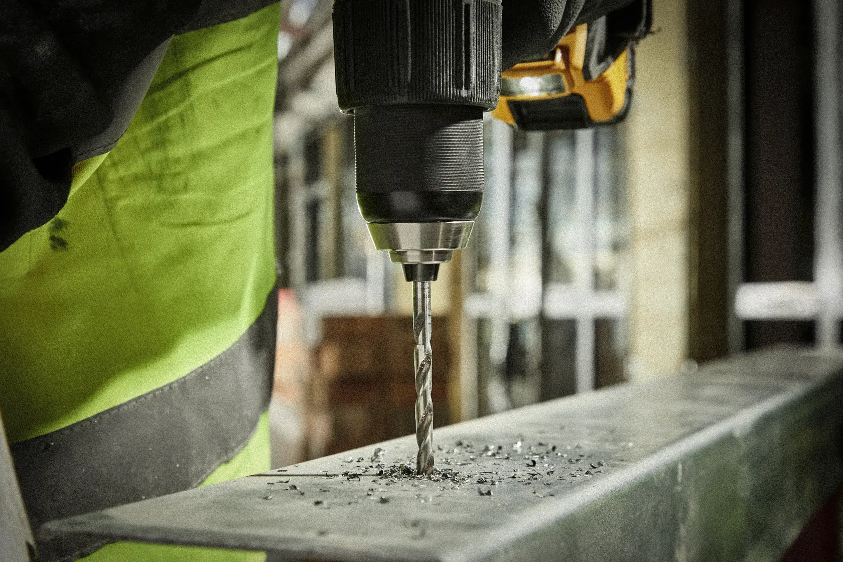 Plano cercano de un taladro perforando metal, con virutas de metal alrededor de la broca.