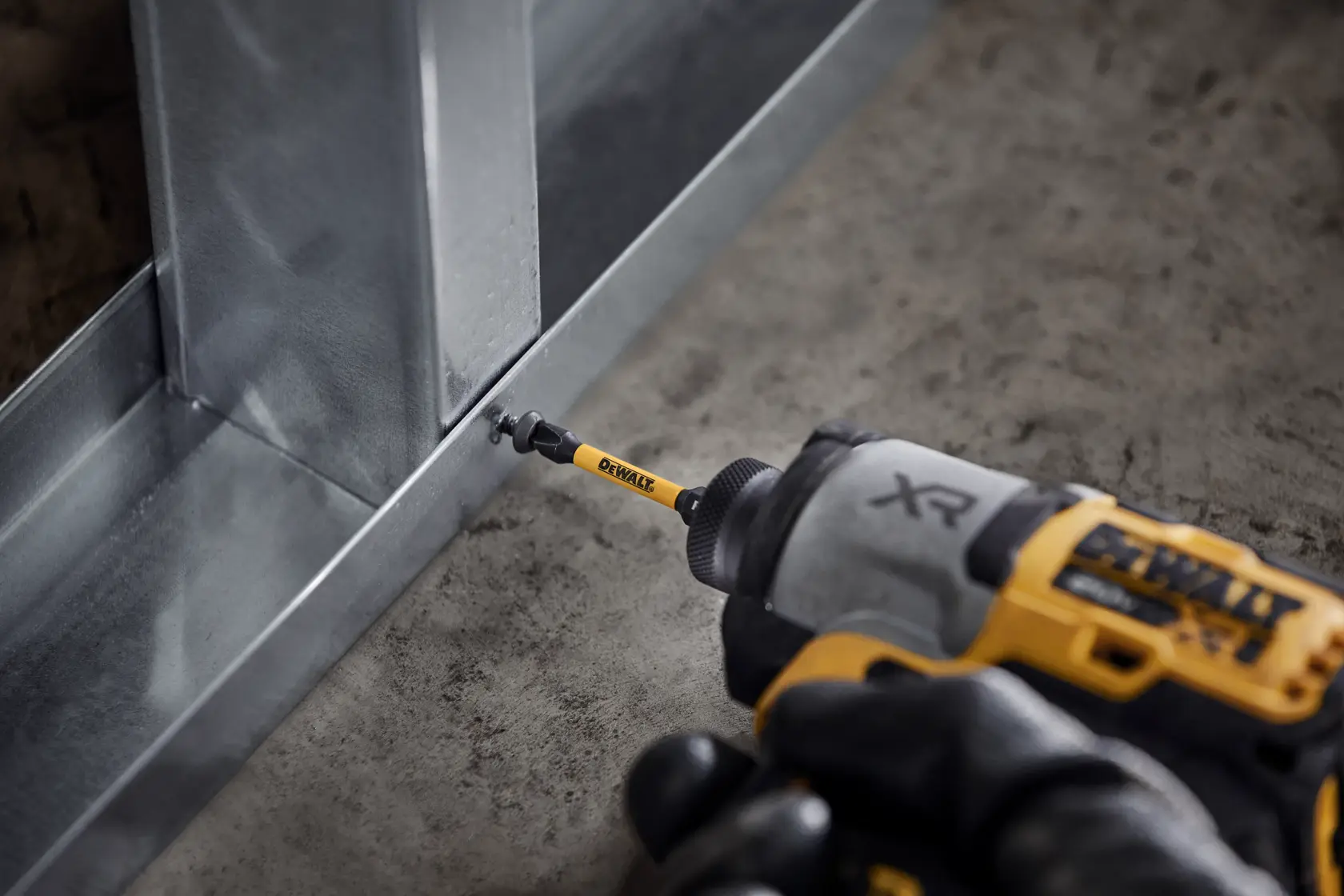 DEWALT Elektrowerkzeug schraubt eine Schraube in einen Metallrahmen am Boden.