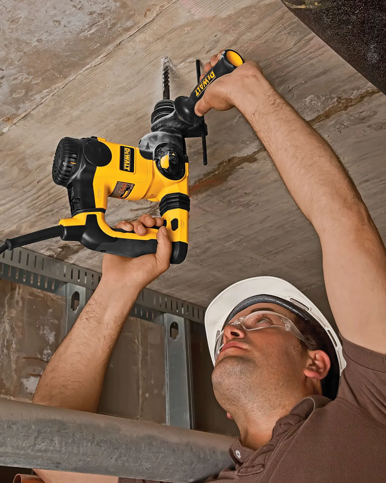 Persona usando taladro DEWALT en el techo, llevando casco y equipo de seguridad.