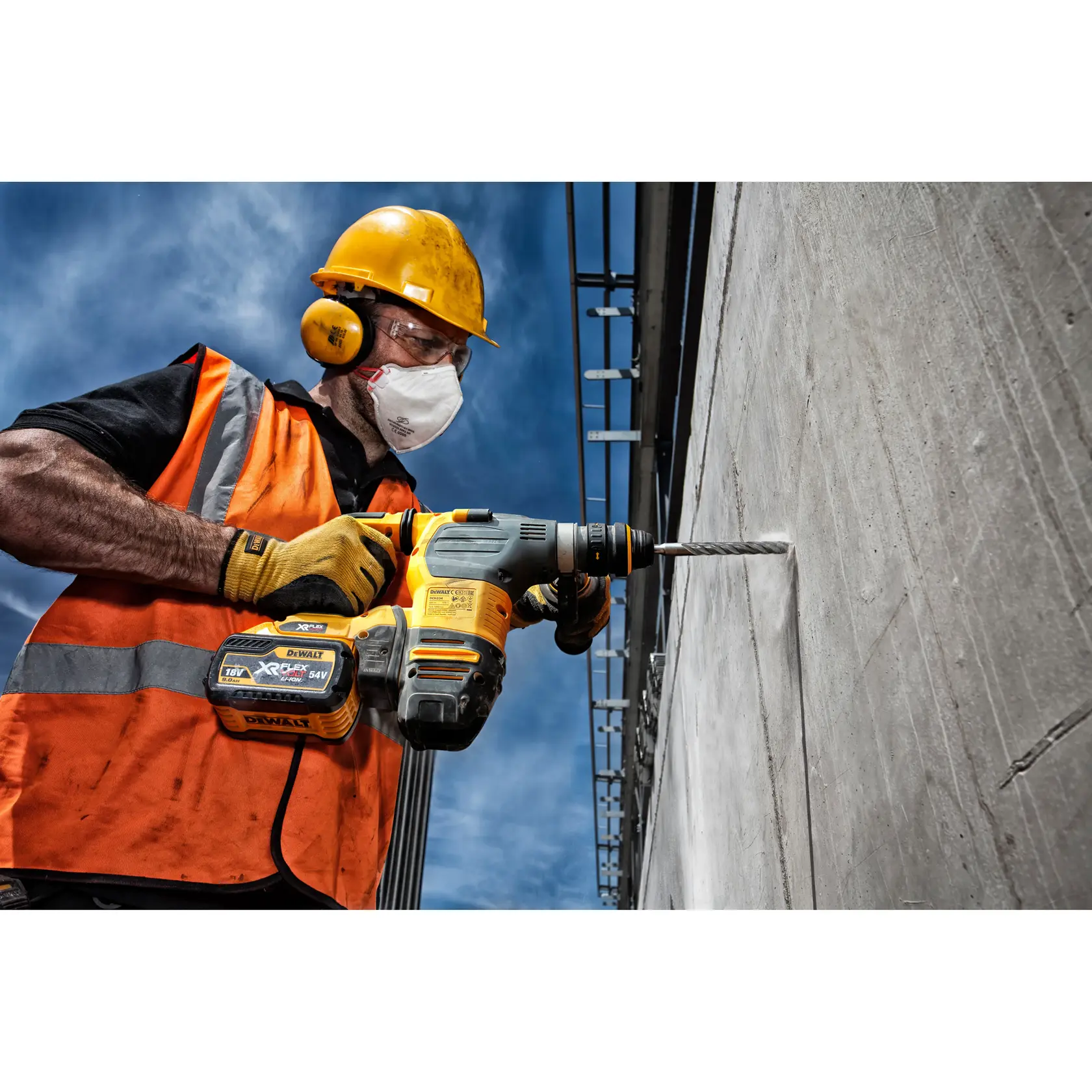 Trabajador perfora pared de concreto con DEWALT DT9548, usando chaleco naranja y casco de seguridad.