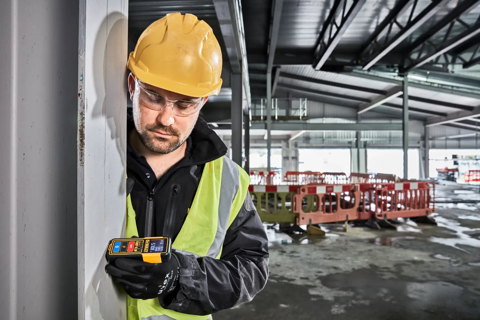 DEWALT DW099S Laser-Entfernungsmesser mit beleuchtetem digitalen Display, das mehrere Messergebnisse anzeigt. Das Gerät hat ein gelbes und schwarzes Gehäuse und beschriftete Tasten für Funktionen wie Einheiten, Entfernung und Bluetooth.