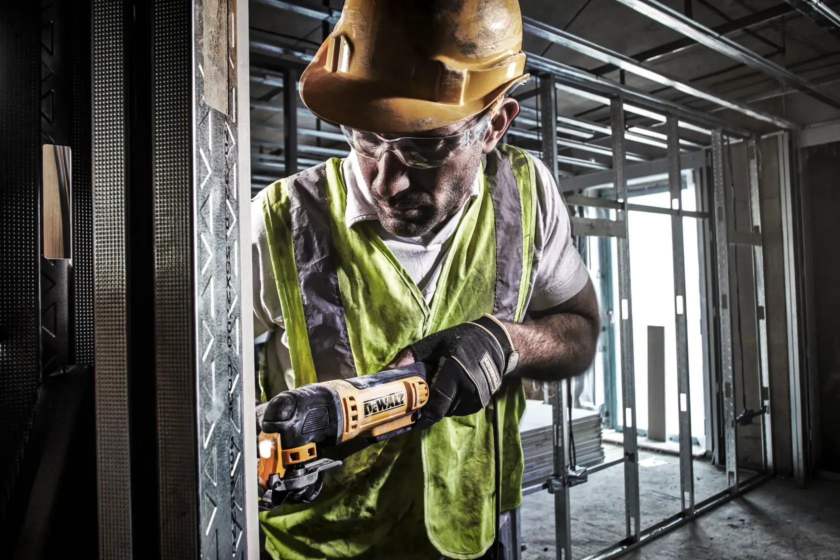Eine Person verwendet ein oszillierendes Multifunktionswerkzeug von DEWALT, um einen Holzboden in der Nähe einer Fußleiste zu schleifen oder zu schneiden.
