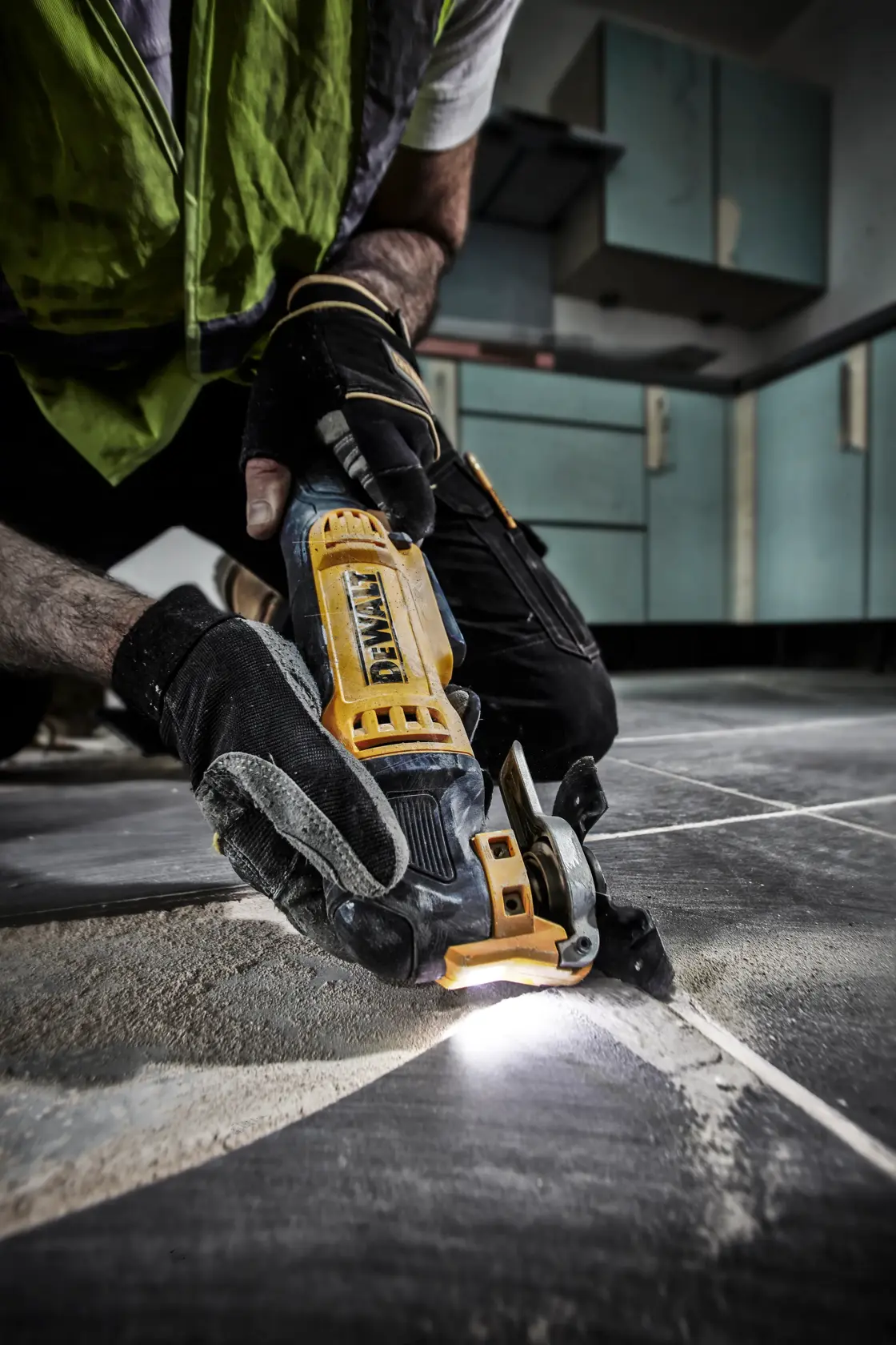 Eine Person verwendet ein DEWALT DWE315 oszillierendes Multifunktionswerkzeug, um eine Holzfußbodenplatte in der Nähe einer Wand zu schneiden.